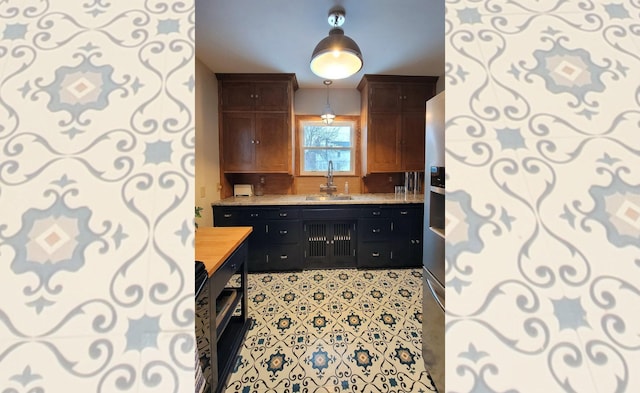 kitchen with decorative light fixtures, butcher block counters, backsplash, and sink