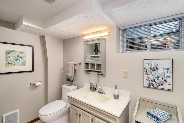 bathroom with a textured ceiling, toilet, and vanity