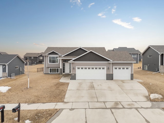 view of front of property featuring a garage, a residential view, concrete driveway, and roof with shingles