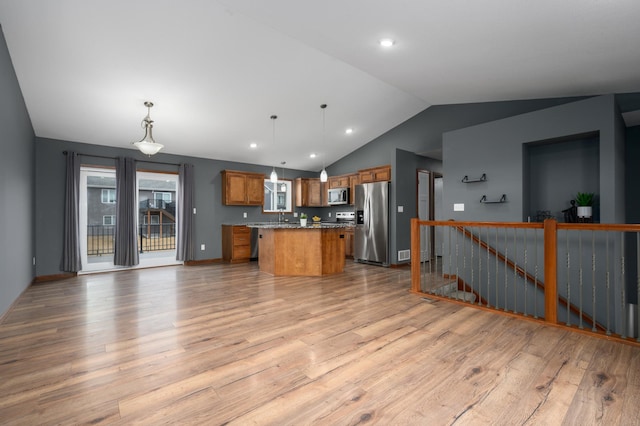 kitchen featuring a center island, appliances with stainless steel finishes, light wood-type flooring, brown cabinets, and pendant lighting