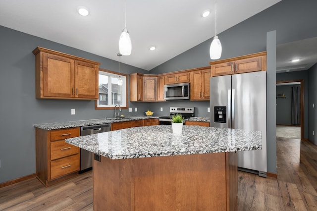 kitchen with stainless steel appliances, hanging light fixtures, brown cabinetry, and a center island