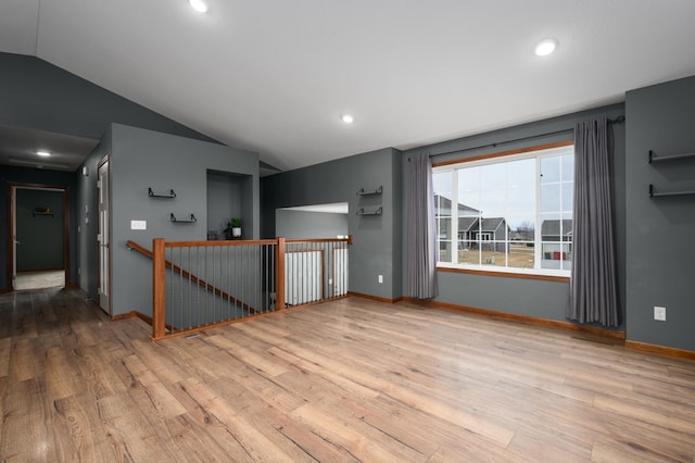 spare room featuring lofted ceiling, light wood-style flooring, baseboards, and recessed lighting