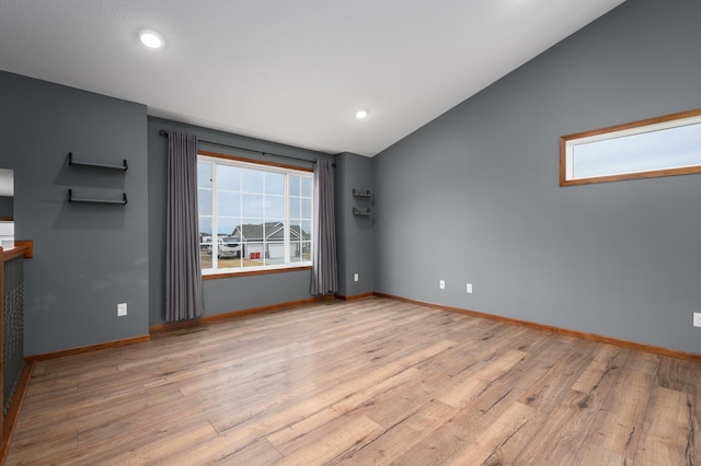 spare room featuring light wood-type flooring, lofted ceiling, baseboards, and recessed lighting