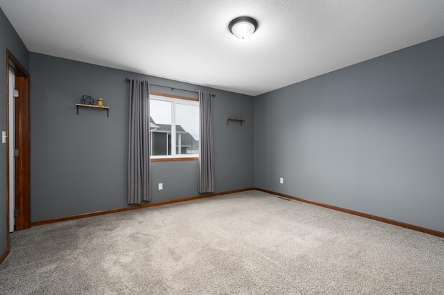 spare room with carpet, visible vents, baseboards, and a textured ceiling