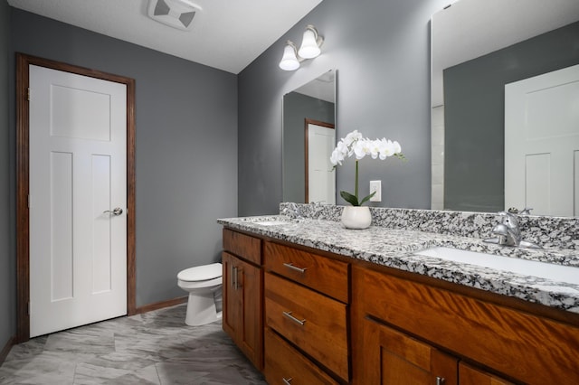 bathroom with toilet, double vanity, a sink, and visible vents