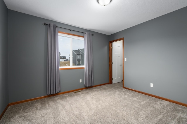 unfurnished room with carpet and baseboards