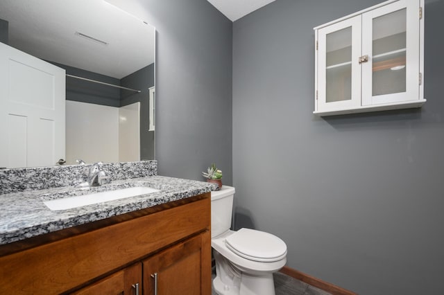 bathroom featuring toilet, visible vents, baseboards, and vanity