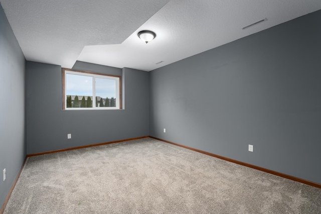 spare room with baseboards, carpet, visible vents, and a textured ceiling