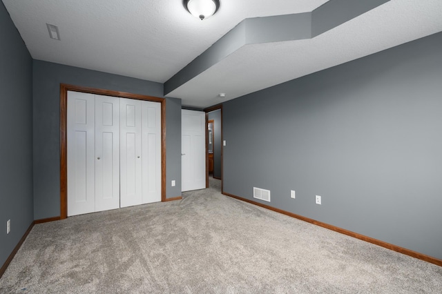 unfurnished bedroom with light carpet, a closet, visible vents, and baseboards