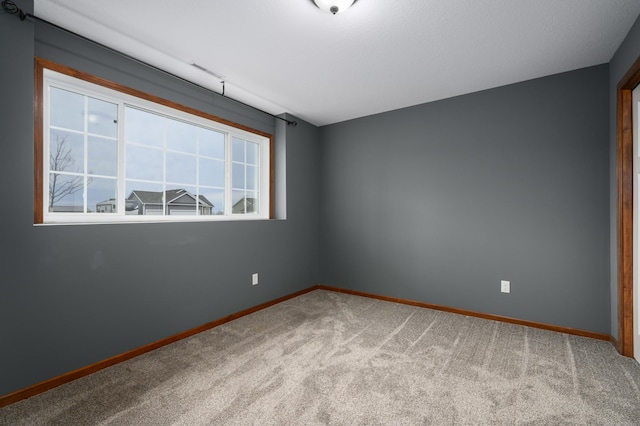 carpeted spare room featuring baseboards