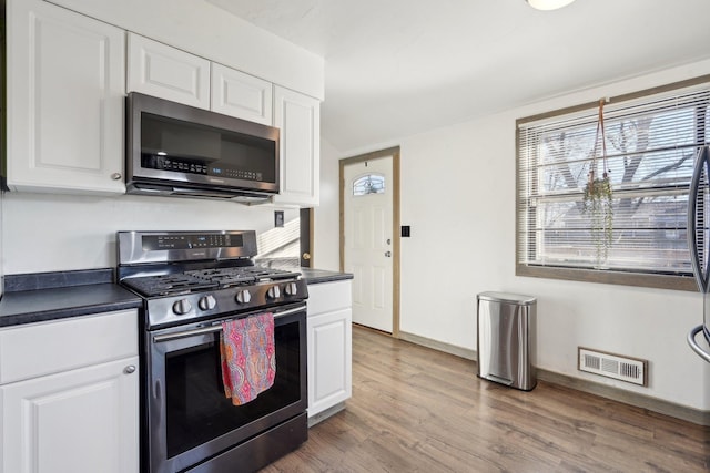 kitchen featuring stainless steel appliances, hardwood / wood-style floors, and white cabinets