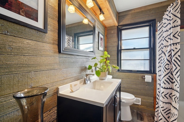 bathroom featuring wooden walls, vanity, wood-type flooring, toilet, and walk in shower