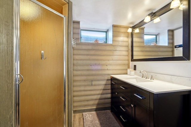 bathroom with vanity, a shower with shower door, and wooden walls