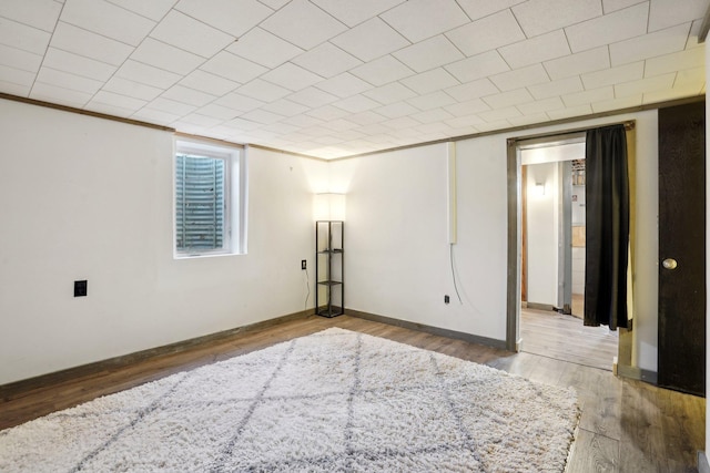 basement with hardwood / wood-style flooring and crown molding