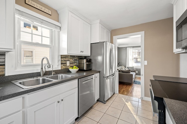 kitchen featuring stainless steel appliances, sink, white cabinets, light tile patterned flooring, and decorative backsplash