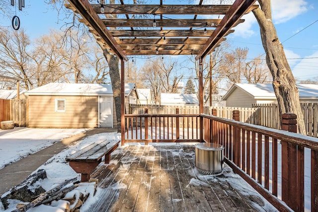 snow covered deck featuring a shed and a pergola