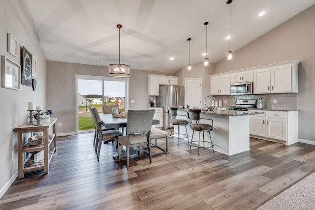 dining room with hardwood / wood-style flooring, high vaulted ceiling, and sink