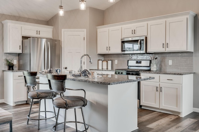 kitchen with decorative light fixtures, appliances with stainless steel finishes, a kitchen island with sink, and white cabinetry