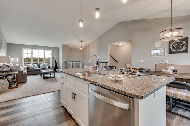 kitchen with light stone counters, stainless steel dishwasher, decorative light fixtures, a kitchen island with sink, and white cabinetry