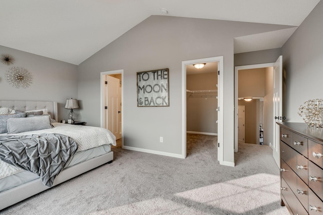 bedroom featuring vaulted ceiling, a closet, a spacious closet, and light carpet