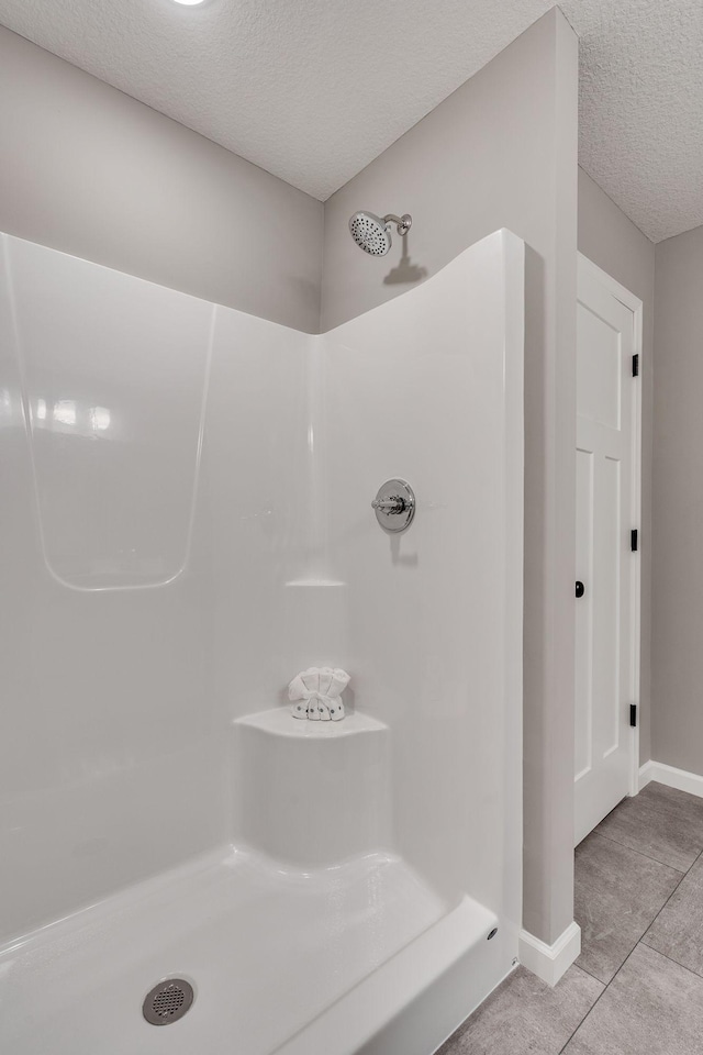 bathroom featuring a textured ceiling, walk in shower, and tile patterned flooring