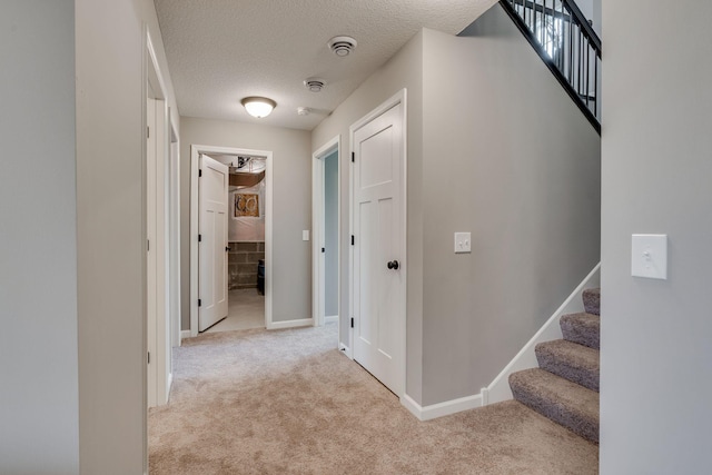 corridor with light colored carpet and a textured ceiling