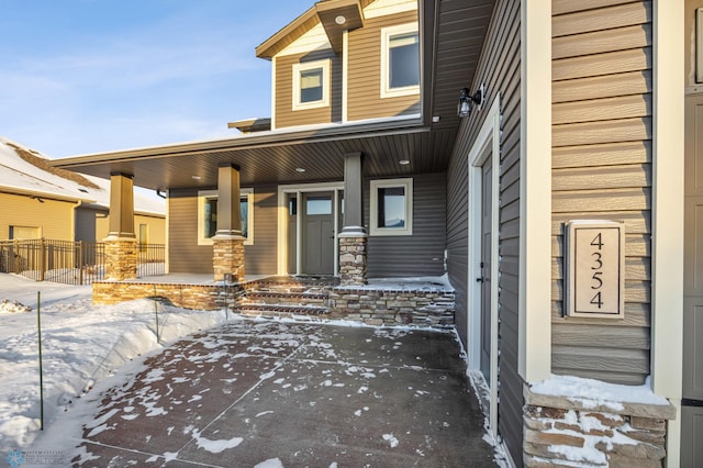 snow covered property entrance featuring a porch