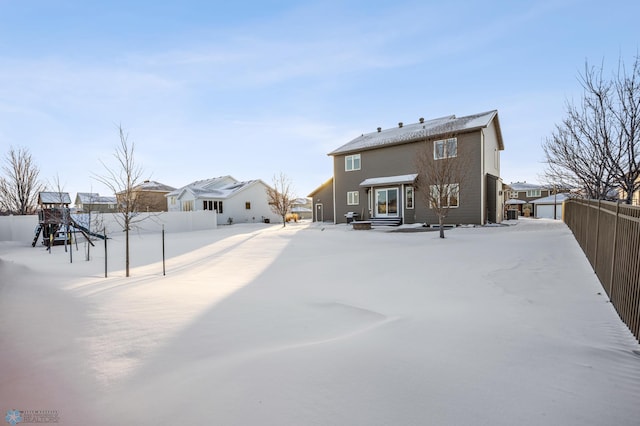 snow covered rear of property featuring a playground