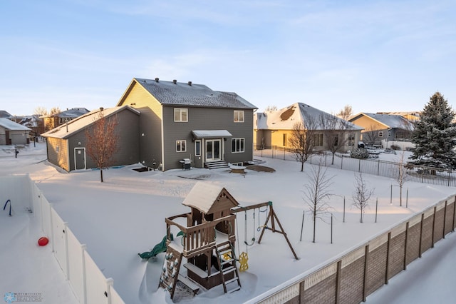 snow covered house featuring a playground