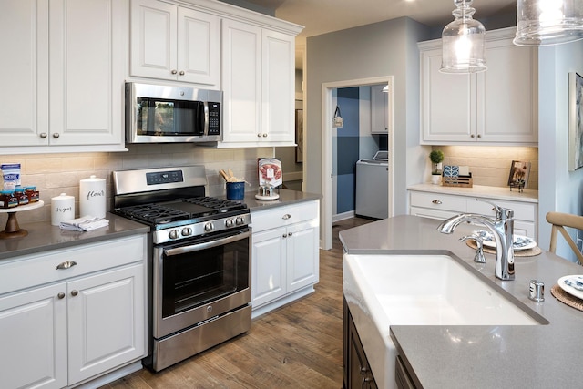 kitchen featuring decorative light fixtures, washer / clothes dryer, sink, white cabinetry, and stainless steel appliances