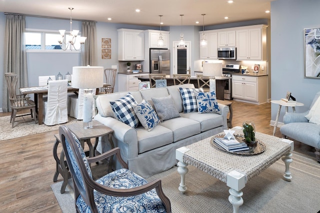 living room with light wood-type flooring and an inviting chandelier