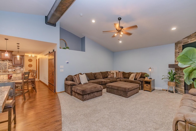 living room featuring high vaulted ceiling, beamed ceiling, ceiling fan, light hardwood / wood-style floors, and a barn door