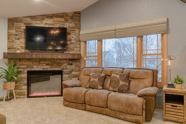 living room featuring carpet floors, plenty of natural light, a stone fireplace, and vaulted ceiling