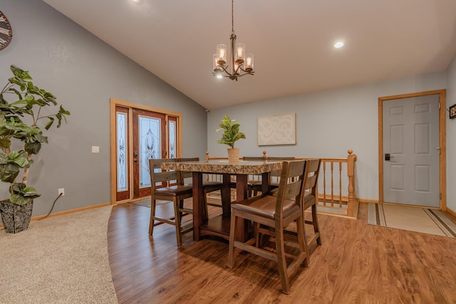 dining room featuring an inviting chandelier, wood-type flooring, and vaulted ceiling