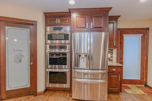 kitchen featuring tasteful backsplash, stainless steel appliances, light stone countertops, and light hardwood / wood-style floors