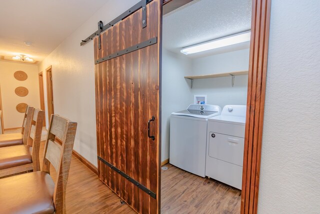 washroom featuring a barn door, washer and clothes dryer, and light hardwood / wood-style floors