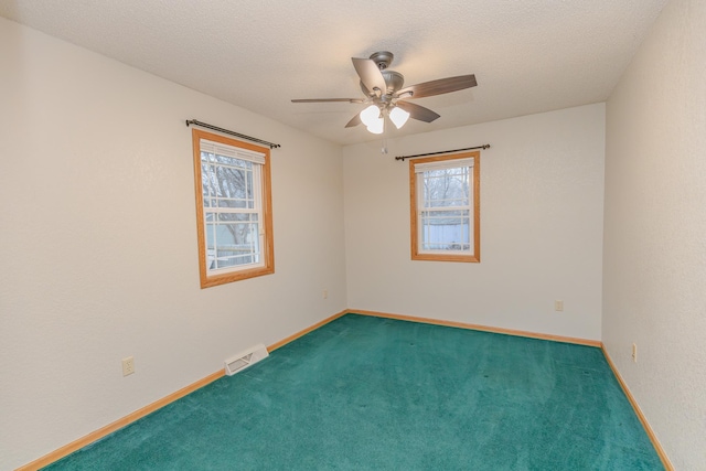 carpeted spare room with ceiling fan and a textured ceiling