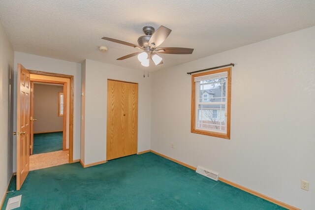 unfurnished bedroom with ceiling fan, dark carpet, a closet, and a textured ceiling