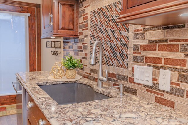 kitchen featuring light stone counters, sink, and decorative backsplash