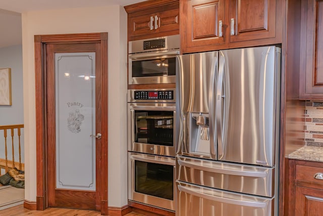 kitchen featuring tasteful backsplash, appliances with stainless steel finishes, and light stone counters