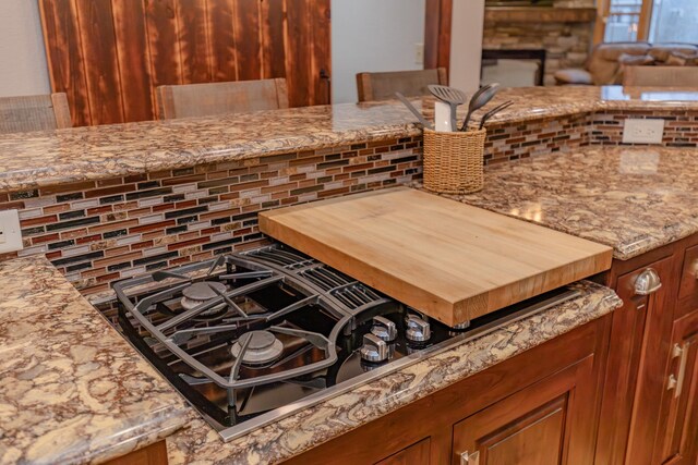 interior details featuring tasteful backsplash, light stone counters, and gas stovetop