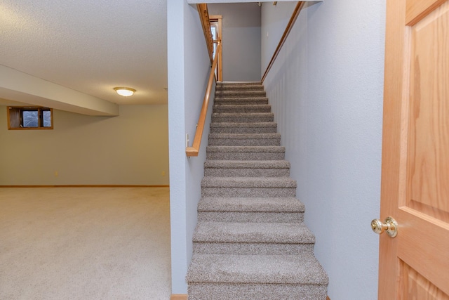 stairway with carpet flooring and a textured ceiling