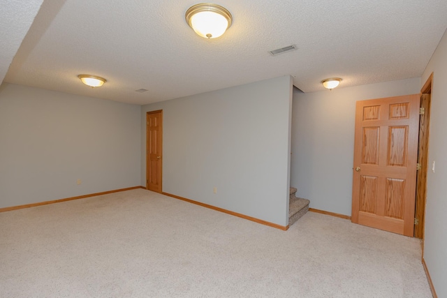 basement featuring light colored carpet and a textured ceiling