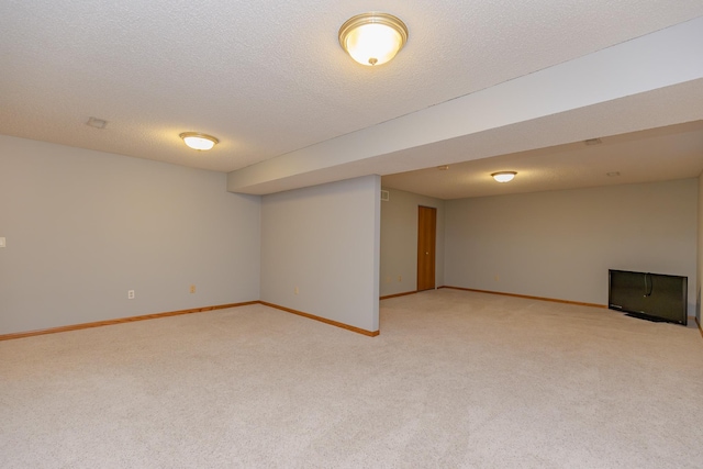 basement featuring light colored carpet and a textured ceiling