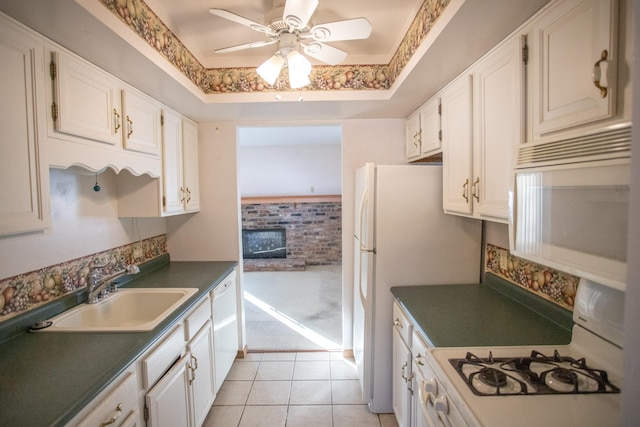 kitchen with sink, white cabinetry, white appliances, light tile patterned floors, and a tray ceiling