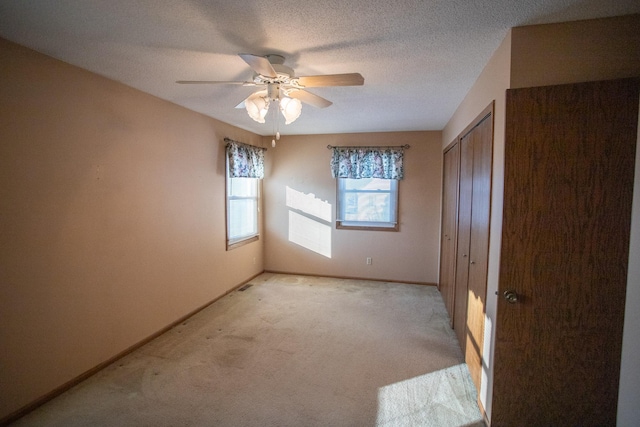 unfurnished room featuring a textured ceiling, ceiling fan, and light colored carpet