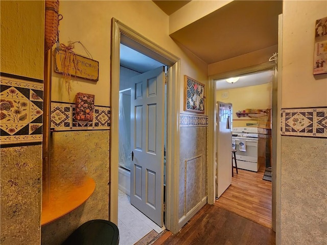 hall with tile walls and light wood-type flooring