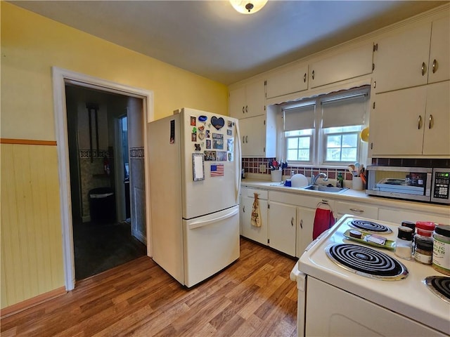 kitchen featuring white appliances, a sink, light wood-style floors, light countertops, and decorative backsplash