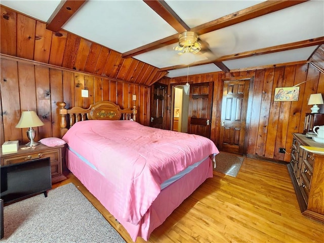 bedroom featuring vaulted ceiling with beams, wood walls, and light wood-style floors