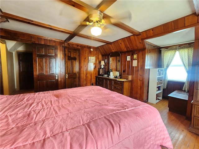 bedroom featuring light wood finished floors, wooden walls, and beamed ceiling